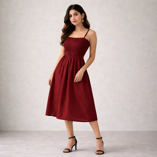 Girl wearing a maroon smocked midi dress against a plain background